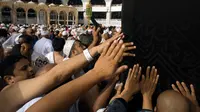 Umat muslim memanjatkan doa di dekat pintu Kabah dengan menyentuhnya selama menjalani ibadah umrah di Masjidil Haram, Mekkah, 4 Mei 2018. Banyak umat muslim yang menyambut bulan Ramadan dengan menjalankan ibadah umrah ke tanah suci. (AP Photo/Amr Nabil)