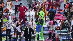 Orang-orang mengarahkan papan SUP mereka selama festival dayung berdiri (stand up paddle) di kanal dayung Olimpiade Krylatskoye, Moskow, Rusia, Minggu (12/9/2021). Festival dihadiri para peserta dalam balutan kostum warna-warni yang menggambarkan aneka karakter dalam tokoh film. (AP/Pavel Golovkin)
