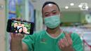 Petugas analis laboratorium Yosaphat Dimaz (28) menunjukkan foto keluarga saat di RSUD Pasar Minggu, Jakarta, Jumat (22/5/2020). Yosaphat Dimaz sudah 2,5 bulan tidak bertemu keluarga selama bertugas menjaga COVID-19 di RSUD Pasar Minggu. (Liputan6.com/Herman Zakharia)