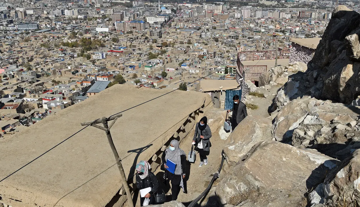 Petugas kesehatan berjalan selama kampanye vaksinasi polio untuk anak di Kabul, Afghanistan pada 8 November 2021. Vaksinasi tersebut merupakan yang pertama sejak Taliban berkuasa di Afghanistan. (WAKIL KOHSAR / AFP)