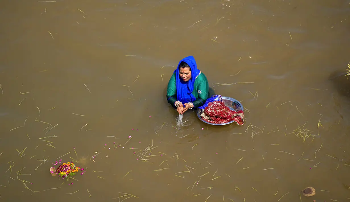 Seorang umat Hindu membenamkan bibit jelai sebagai persembahan saat Festival Navratri di Sungai Tawi, Jammu, India, 10 April 2022. Sesaji tersebut dibuat sebagai bagian dari ritual menandai berakhirnya festival selama sembilan hari. (AP Photo/Channi Anand)