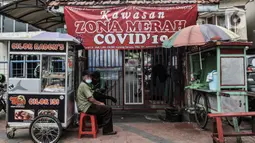 Sejumlah pedagang kaki lima berjualan di depan gang yang diberi spanduk zona merah COVID-19 di kawasan Paseban, Jakarta, Rabu (10/2/2021). Zona merah di Jakarta Barat sebanyak 13 RW, Jakarta Timur 6 RW, Jakarta Utara 4 RW, dan Kepulauan Seribu 2 RW. (merdeka.com/Iqbal S. Nugroho)