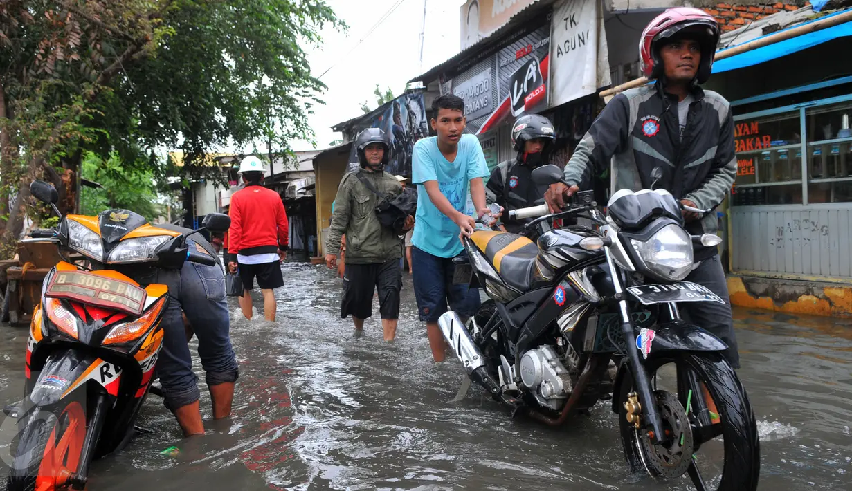 Warga melawati jalanan yang banjir di kawasan Jakarta Barat, Jumat (26/2). Ketinggian banjir mencapai 50-60cm.  (Liputan6.com/Faisal R Syam)