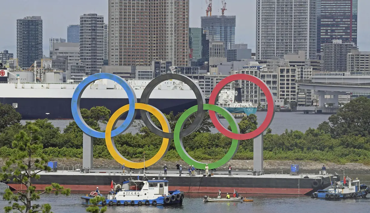 Para pekerja bersiap melepas cincin Olimpiade yang mengambang di air setelah Olimpiade Musim Panas 2020 berakhir pada 8 Agustus, di Tokyo, Rabu (11/8/2021). Setelah ini, Kota Paris, Prancis, akan menjadi tuan rumah olimpiade pada 2024 mendatang. (Kyodo News via AP)