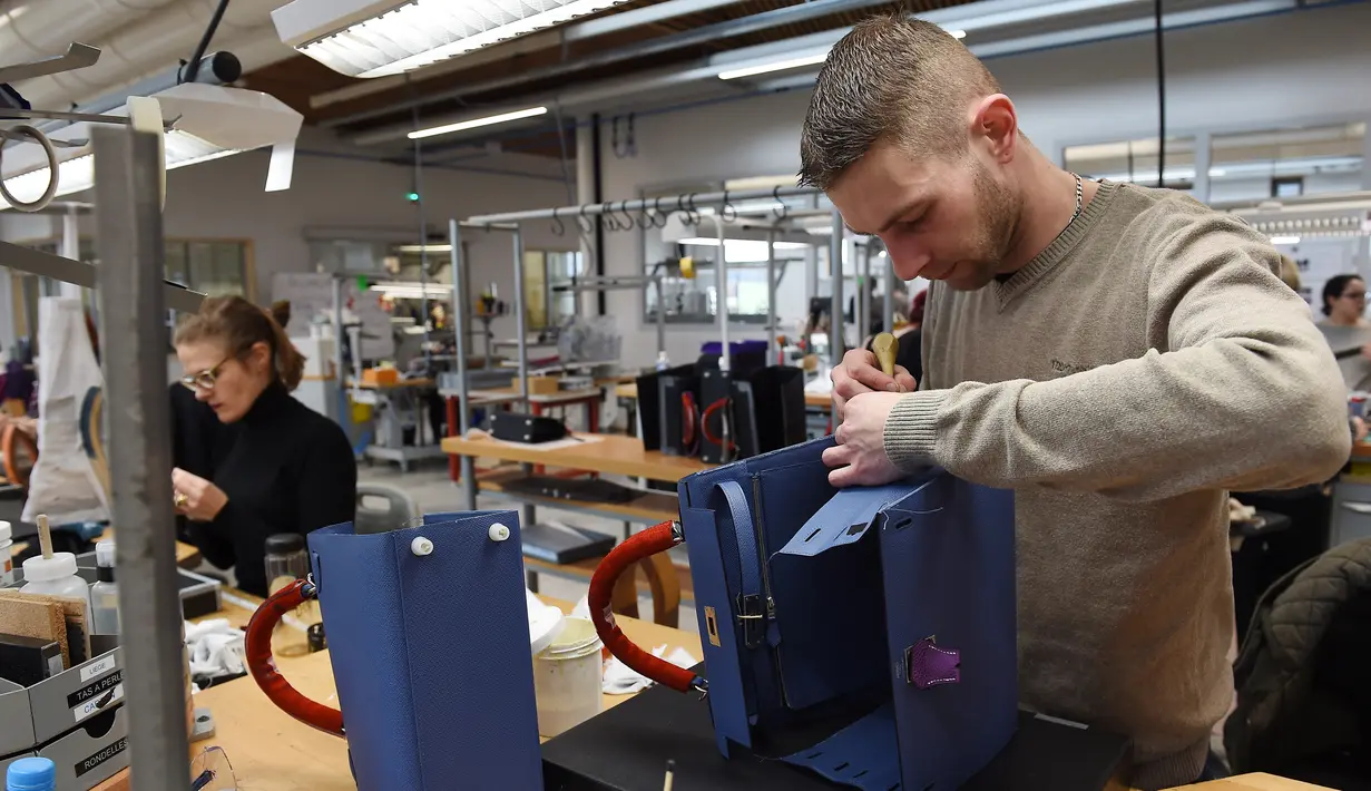 Proses merapikan bagian tas di bengkel produsen barang-barang mewah Hermes di Allenjoie, Perancis, Kamis (5/4). Hermes merupakan brand fashion eksklusif asal Prancis. (SEBASTIEN BOZON/AFP)