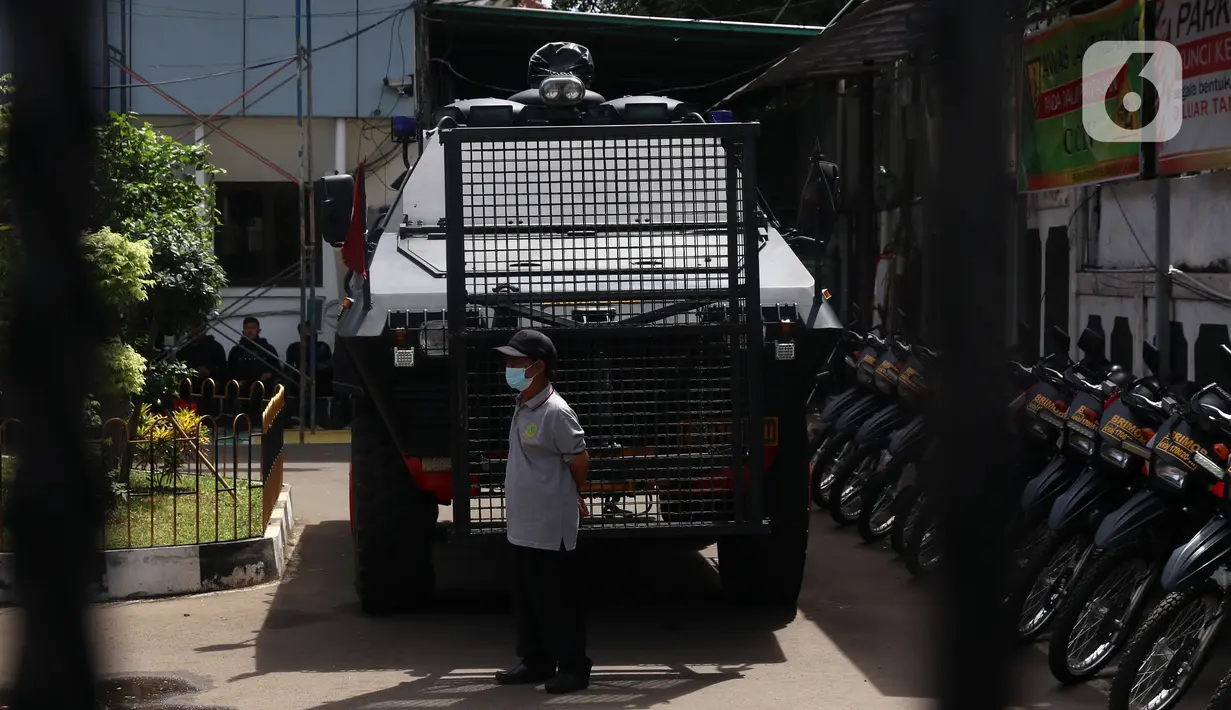 Seorang pria berdiri di depan mobil polisi yang terparkir di area Pengadilan Negeri Jakarta Selatan, Senin (4/1/2021). Pengamanan ratusan aparat kepolisian dilakukan untuk mengantisipasi pergerakan masa pada saat sidang praperadilan Rizieq Shihab. (Liputan6.com/Angga Yuniar)