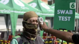 Pengemudi ojek online dicek suhu tubuhnya saat menjalani swab test COVID-19 di Alam Sutra, Tangerang Selatan, Banten, Selasa (21/7/2020). Swab test gratis yang digelar Pemerintah Provinsi Banten melalui Dinas Kesehatan tersebut diikuti oleh 700 pengemudi ojek online. (merdeka.com/Dwi Narwoko)
