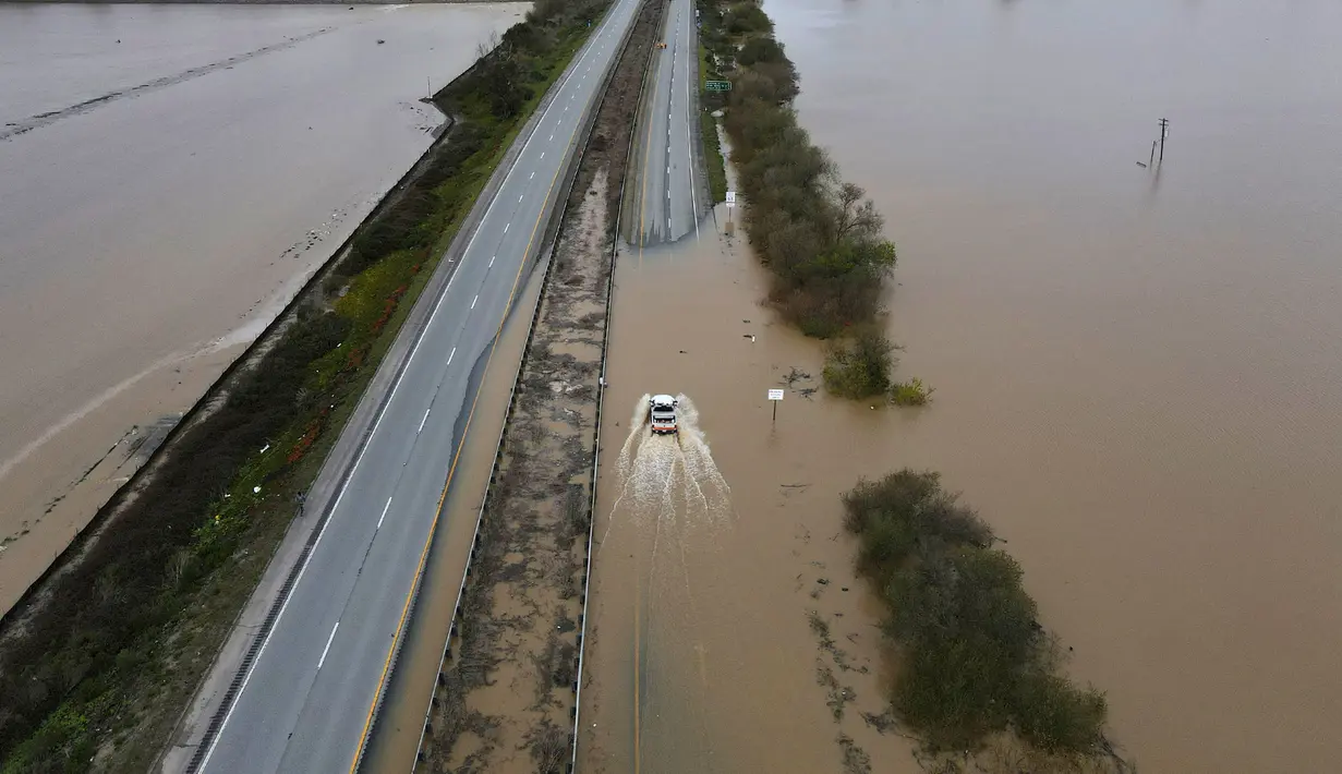 Sebuah kendaraan CalTrans melaju ke utara melewati banjir yang menutup State Highway 1 di jalur Santa Cruz County, California, Amerika Serikat, 12 Maret 2023. Lebih dari 50 orang harus diselamatkan oleh Garda Nasional California akibat banjir besar awal pekan lalu. (Shmuel Thaler/The Santa Cruz Sentinel via AP)