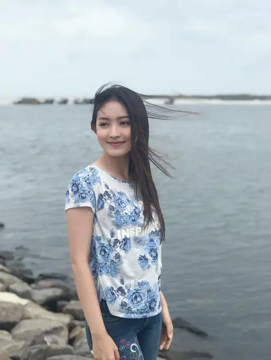 Berada di tepi pantai, kali ini Natasha hanya memakai kaos bermotif bunga-bunga dengan celana jeansnya.  (Instagram/natashawilona12)