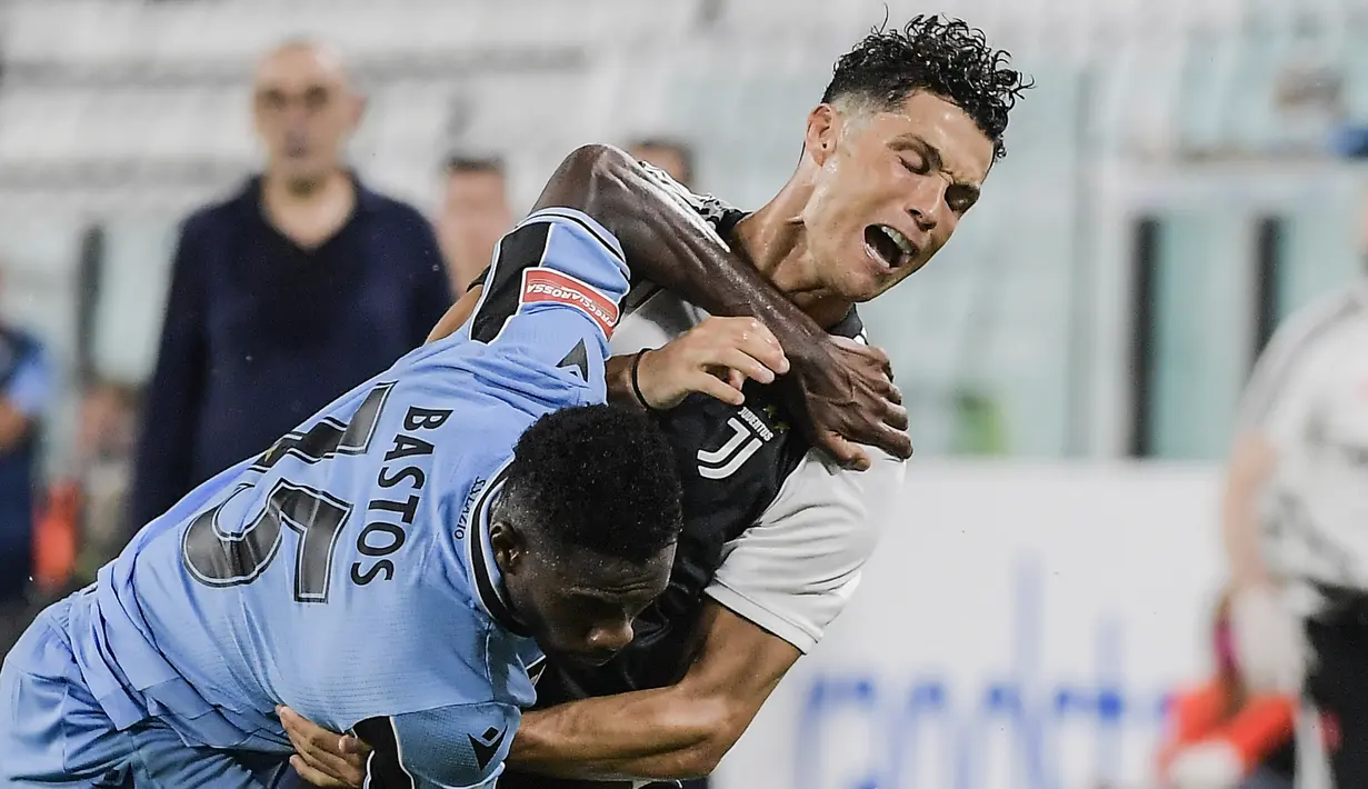 Pemain Juventus Cristiano Ronaldo (kanan) berebut bola dengan pemain Lazio Bastos pada pertandingan Serie A di Allianz Stadium, Turin, Italia, Senin (20/7/2020). Dua gol Ronaldo membawa Juventus menang 2-1. (Marco Alpozzi/LaPresse via AP)