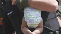 Seorang polisi Hazleton menggendong seorang bayi setelah kebakaran terjadi di sebuah gedung apartemen di Hazleton, Pennsylvania (26/7/2019). Pemadam kebakaran kota menggunakan truk menyelamatkan penghuni dari lantai tiga gedung. (Warren Ruda/Hazleton Standard-Speaker via AP)