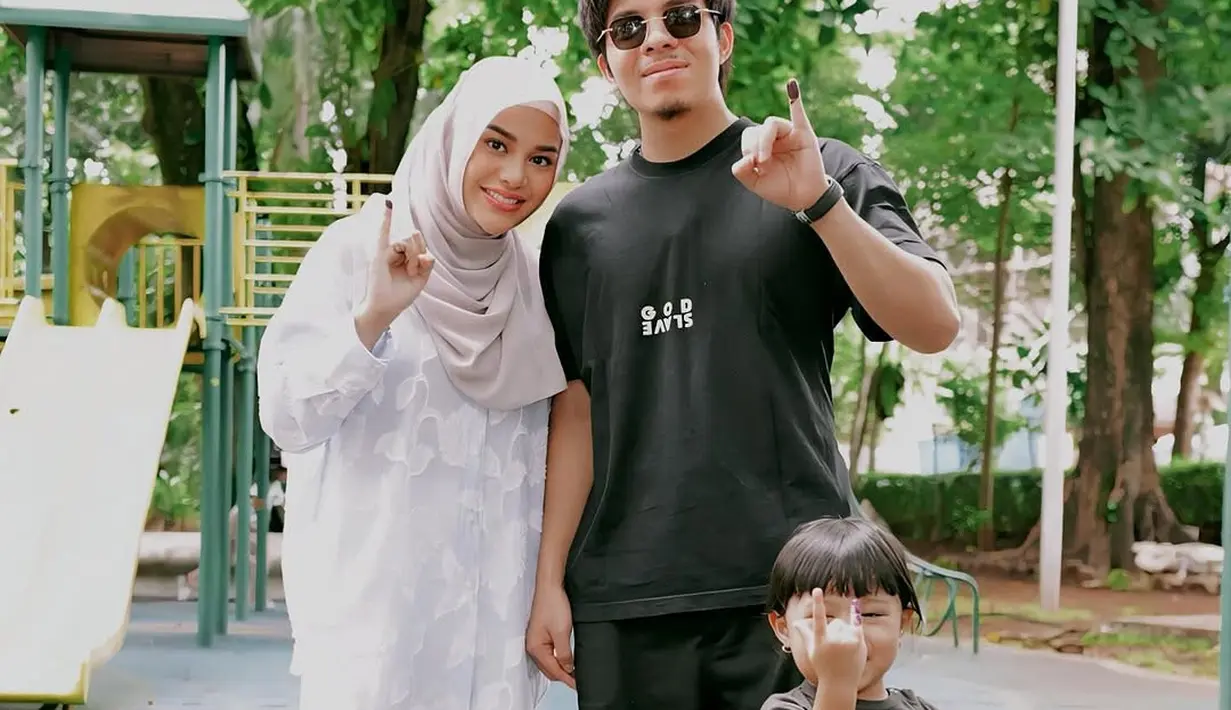 Atta Halilintar dan Aurel Hermansyah kenakan busana yang kontas namun saling melengkapi. Aurel kenakan kemeja lace dengan celana putih dan hijab keabuan. Sementara Atta tampil serba hitam padukan t-shirt dan celana panjang [@attahalilintar]