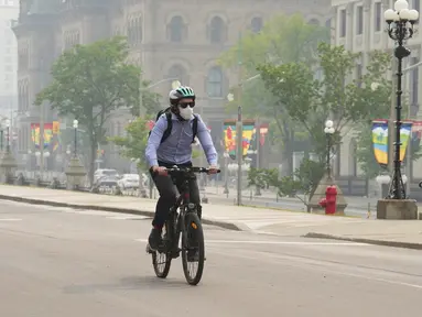 Seorang pengendara sepeda memakai masker saat kualitas udara yang buruk karena asap dari kebakaran hutan di Ontario dan Quebec di Ottawa, Kanada, Selasa (6/6/2023). (Sean Kilpatrick/The Canadian Press via AP)
