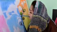 Foto yang diambil pada 5 Desember 2019 menunjukkan seniman Robaba Mohammadi melukis menggunakan mulut di studionya di Kabul. Untuk membuktikan bahwa stigma negatif tentang perempuan dan disabilitas salah, Robaba mengembangkan bakat di bidang seni lukis. (NOORULLAH SHIRZADA/AFP)