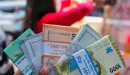 Warga memperlihatkan pecahan uang tunai baru di layanan kas keliling Bank Indonesia di Pasar Kopro, Jakarta Barat, Rabu (29/3/2023). (Liputan6.com/Angga Yuniar)