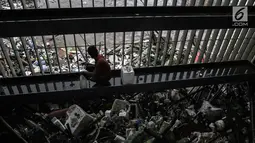 Seorang petugas membersihkan sampah yang tersangkut di Pintu Air Manggarai, Jakarta, Senin (5/2). Hingga sore hari, Pintu Air Manggarai berada pada status siaga 1 dengan ketinggian air 800cm. (Liputan6.com/Faizal Fanani)