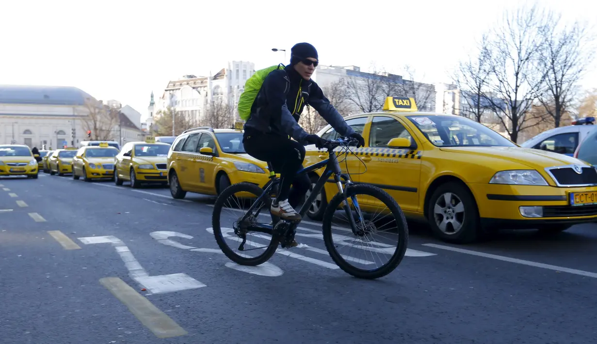 Warga melintas dijalanan kota Budapest yang diblokir oleh Sejumlah Sopir taksi di Budapest, Hongaria, (18/1). Pengemudi taksi konvensional memprotes taksi online Uber yang beroperasi d Hongaria. (REUTERS / Laszlo Balogh)