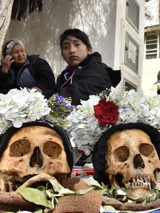 Wanita pribumi Aymara menyembah tengkorak manusia selama Festival Natitas di pemakaman La Paz, Bolivia pada 8 November 2018.  Menurut tradisi Andean, orang-orang percaya menjaga "natitas" di rumah dapat melindungi keluarga mereka. (AIZAR RALDES/AFP)