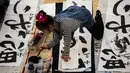 Seorang peserta mencelupkan tinta untuk membuat tulisan Jepang saat mengikuti lomba kaligrafi Tokyo, Jepang (5/1). (AFP Photo/Behrouz Mehri)