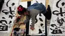 Seorang peserta mencelupkan tinta untuk membuat tulisan Jepang saat mengikuti lomba kaligrafi Tokyo, Jepang (5/1). (AFP Photo/Behrouz Mehri)