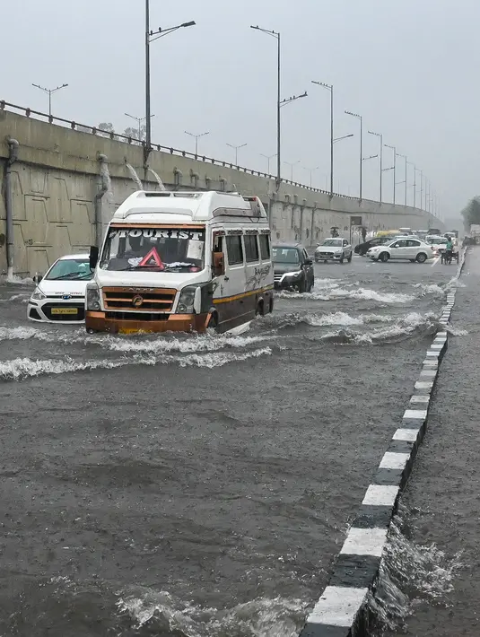 Sejumlah mobil melewati jalan yang tergenang air saat hujan lebat di New Delhi, India (1/9/2021). hujan lebat menyebabkan gangguan lalu lintas dan genangan air di daerah dataran rendah. (AFP/Prakash Singh)