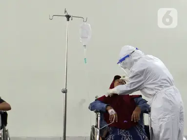 Petugas medis (kanan) yang mengenakan hazmat melakukan tes usap PCR di selasar IGD RSUD Cengkareng, Jakarta, Rabu (23/6/2021). Meningkatnya kasus COVID-19 di Ibu Kota Jakarta dalam beberapa hari terakhir mengakibatkan rumah sakit kewalahan. (Liputan6.com/Herman Zakharia)
