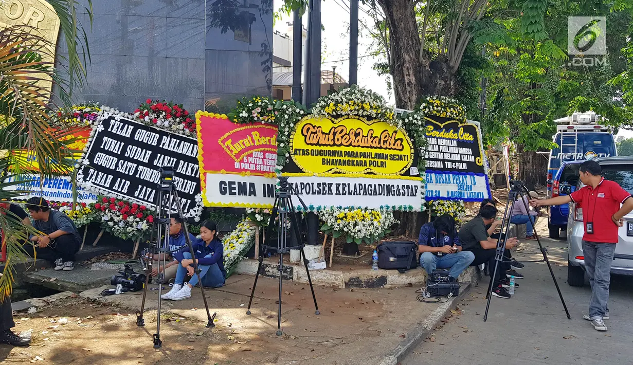 Sejumlah awak media berada di dekat karangan bunga di komplek Mako Brimob Kelapa Dua, Depok, Jawa Barat, Jumat (11/5). Karangan bunga ucapan bela sungkawa bertuliskan 'kami tidak takut, kami bersama Polri'. (Liputan6.com/Herman Zakharia)