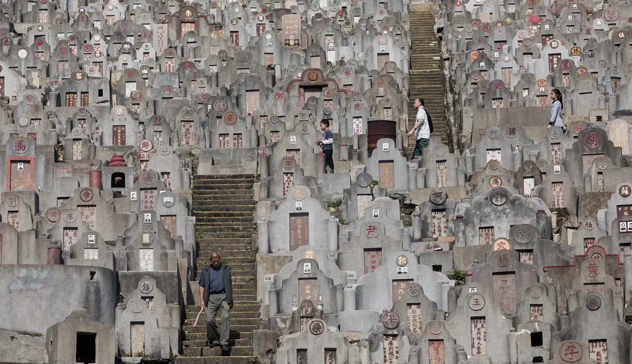 Warga berjalan melewati batu nisan saat berziarah untuk menyambut festival Ching Ming di Hong Kong (2/4). Festival tradisional Tiongkok ini dilaksanakan pada hari ke-104 setelah titik balik Matahari di musim dingin. (AFP/Dale De La Rey)