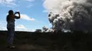 Seorang wanita mengambil gambar kepulan abu vulkanik dari gunung berapi Kilauea di Big Island Hawaii (15/5). Sejauh ini, sudah ada 40 rumah dan bangunan lainnya yang hancur terkena lava yang dimuntahkan oleh gunung Kilauea. (Mario Tama/Getty Images/AFP)