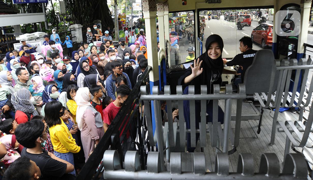 Warga antre masuk bus wisata Uncal di depan Balai Kota Bogor, Bogor, Jawa Barat, Minggu (29/5/2022). Bus wisata gratis yang disediakan untuk mengelilingi kawasan Kebun Raya Bogor setiap hari Sabtu dan Minggu ini mulai beroperasi kembali pascapandemi. (merdeka.com/Arie Basuki)