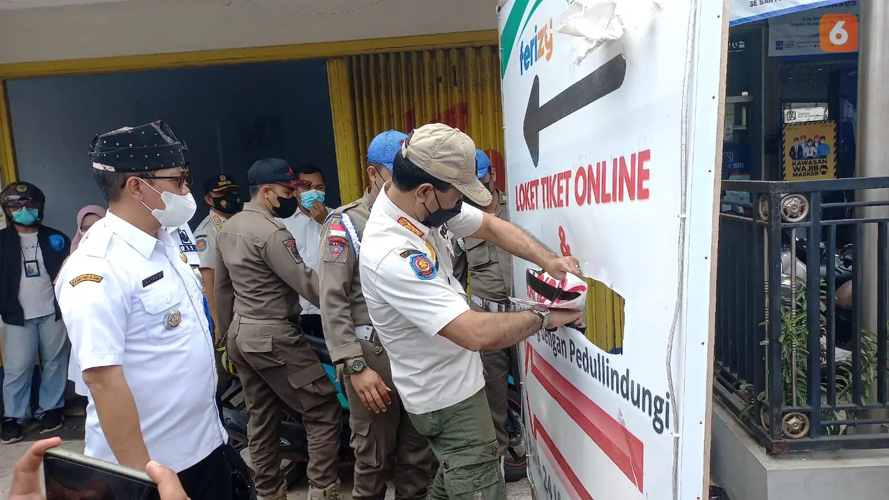 Satpol PP Banyuwangi membongkar banner rapid tes antigen ilegal di Kawasan Pelabuhan Ketapang Banyuwangi. (Hermawan Arifianto/Liputan6.com)