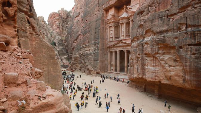 Situs Keajaiban Dunia Petra: Wisatawan jalan-jalan saat mengunjungi kota arkeologi Petra, Yordania, Kamis (21/11/2019). Petra ditetapkan sebagai salah satu dari Tujuh Keajaiban Dunia Baru oleh Yayasan New7Wonders pada tahun 2017. (AHMAD ABDO/AFP)
