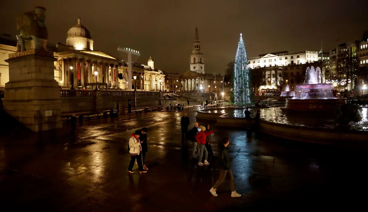 Orang-orang melewati pohon Natal setelah tradisi penyalaan lampu di Trafalgar Square, London, Kamis (6/12). Setiap tahun London mendapat pohon Natal dari Norwegia sebagai tanda terima kasih atas dukungan Inggris selama perang dunia II. (AP/Matt Dunham)