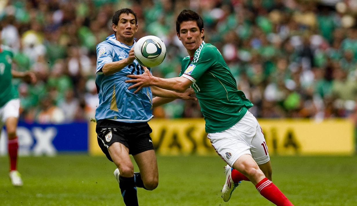 Striker Meksiko, Marco Bueno (kanan) berebut bola dengan bek Uruguay, Alejandro Furia pada laga final Piala Dunia U-17 2011 di Azteca Stadium, Meksiko (10/7/2011). Pada Piala Dunia U-17 2011 yang digelar di Meksiko pada 18 Juni hingga 10 Juli 2011, tuan rumah Meksiko sukses menjadi juara setelah mengalahkan Uruguay dengan skor 2-0 di laga final. Dua gol kemenangan Meksiko dicetak Antonio Briseno dan Giovani Casillas. (AFP/Alfredo Estrella)