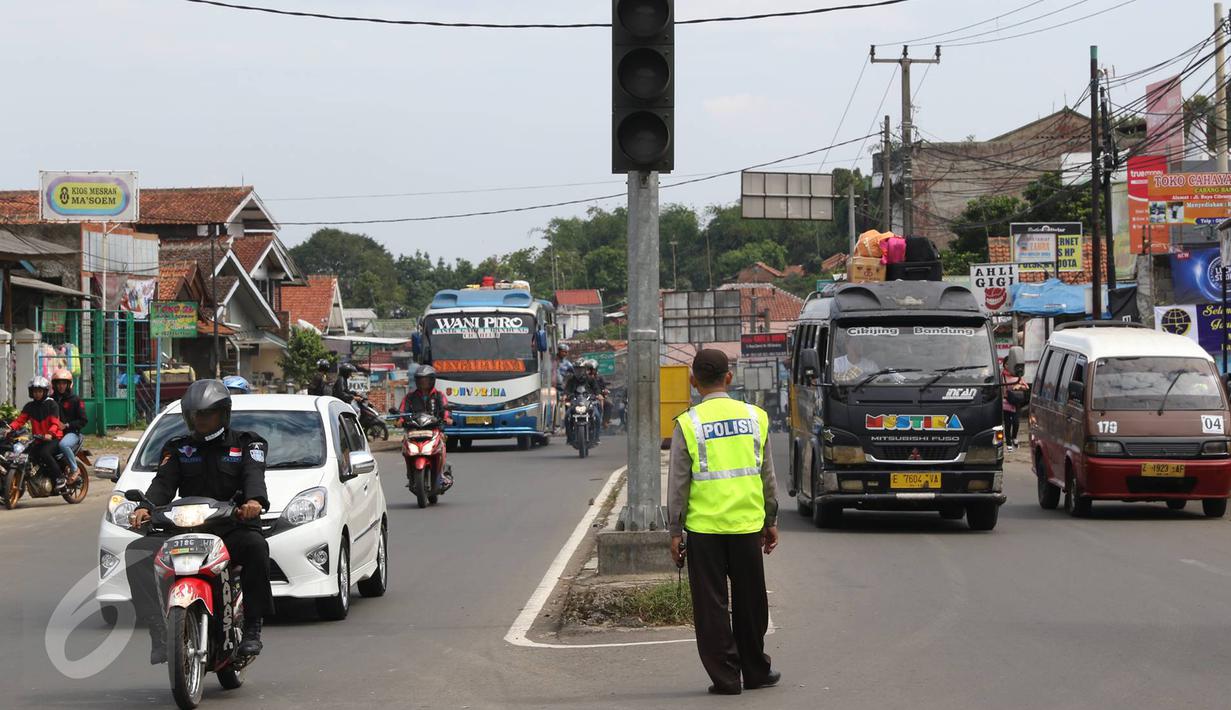 Petugas polisi berjaga di pertigaan Jatinangor, Sumedang, Jawa Barat, Sabtu (2/7). Mengatasi kepadatan kendaraan pemudik, petugas melakukan sistem pengalihan arus dengan menutup jalur dari arah Sumedang menuju Bandung Kota (Liputan6.com/Immanuel Antonius)