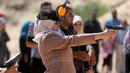 Pelatih memberikan arahan pada seorang gadis Palestina yang tengah belajar menembak saat mengikuti pelatihan dengan anggota Perlindungan dan Keamanan Hamas di Khan Younis di Jalur Gaza, Minggu (24/7). (REUTERS/ Ibraheem Abu Mustafa)