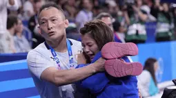 Pelatih berusaha menenangkan  Uta Abe yang menangis histeris. Abe merupakan juara dunia empat kali dan merupakan salah satu judoka favorit untuk memenangi medali emas. (AP Photo/Eugene Hoshiko)