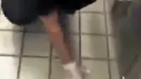 Seorang pegawai wanita terlihat melempar sepotong roti burger ke lantai dan kemudian menggunakan roti itu untuk membersihkan lantai. 