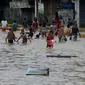 Anak-anak bermain air saat banjir menggenangi Jalan Jatinegara Barat, Jakarta, Kamis (2/1/2020). Hujan yang terjadi kemarin malam membuat Kali Ciliwung meluap ke jalan. (merdeka.com/Imam Buhori)