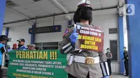 Seorang Polwan Direktorat Lalu Lintas Polda Jawa Tengah menunjukkan poster Cegah Covid-19 saat sterilisasi puluhan angkutan bus yang masuk di Terminal Bawen, Jumat (27/3/2020). (Liputan6.com/Gholib)