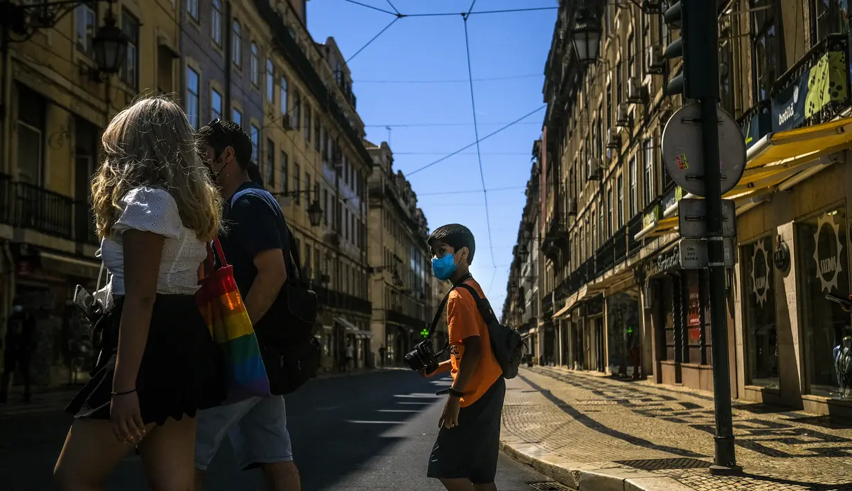 Turis menyeberang jalan di pusat kota Lisbon (14/7/2021). Pemerintah berusaha untuk mengendalikan kebangkitan infeksi virus corona, karena varian Delta yang lebih menular. (AFP/Patricia De Melo Moreira)