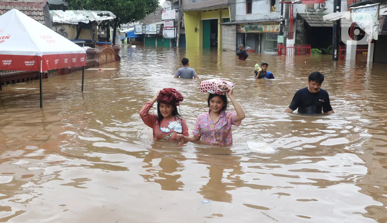 Warga melintasi banjir di perumahan Ciledug Indah, Tangerang, Rabu (1/1/2020). Banjir setinggi dada orang dewasa terjadi akibat meluapnya kali angke. (Liputan6.com/Angga Yuniar)