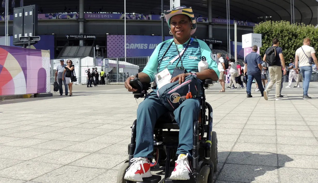Seorang volunteer disabilitas, Ndieme Lame berpose di depan Stade de France saat Olimpiade Paris 2024 pada 7 Agustus 2024. (AP Photo/Tom Nouvian)