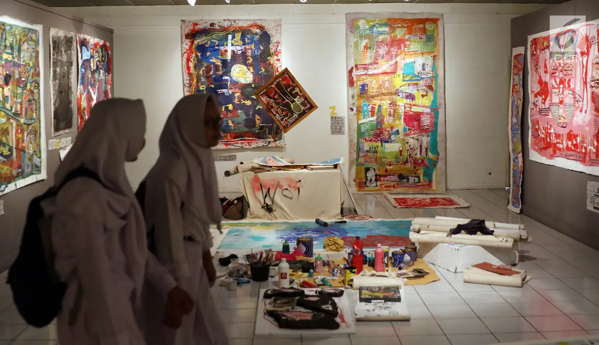 Dua orang siswi melintas di depan karya yang dipamerkan dalam pameran bertajuk Jakarta Open Studio di Taman Ismail Marzuki, Jakarta, Senin (17/7).(Liputan6.com/Immanuel Antonius)
