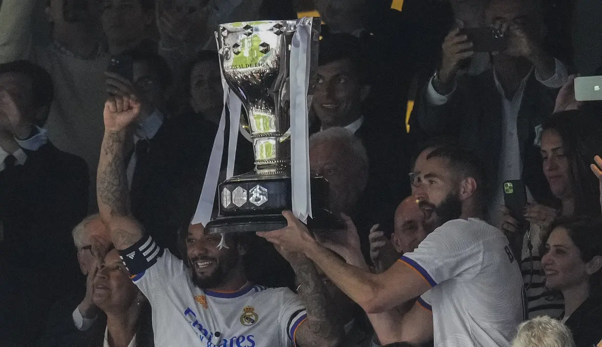 <p>Bek Real Madrid, Marcelo (kiri) dan Karim Benzema mengangkat trofi untuk merayakan gelar La Liga Spanyol usai pertandingan melawan Espanyol di stadion Santiago Bernabeu di Madrid, Sabtu (30/4/2022). (AP Photo/Bernat Armangue)</p>