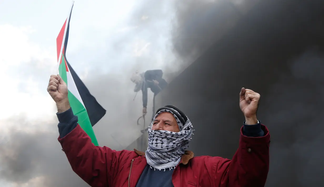 Seorang pria membawa bendera Palestina saat aksi di perbatasan Palestina-Israel, Ramallah, Jumat (17/2). Aksi tersebut untuk memperingati 12 tahun protes mereka atas tembok pemisah tersebut. (AP Photo / Majdi Mohammed)