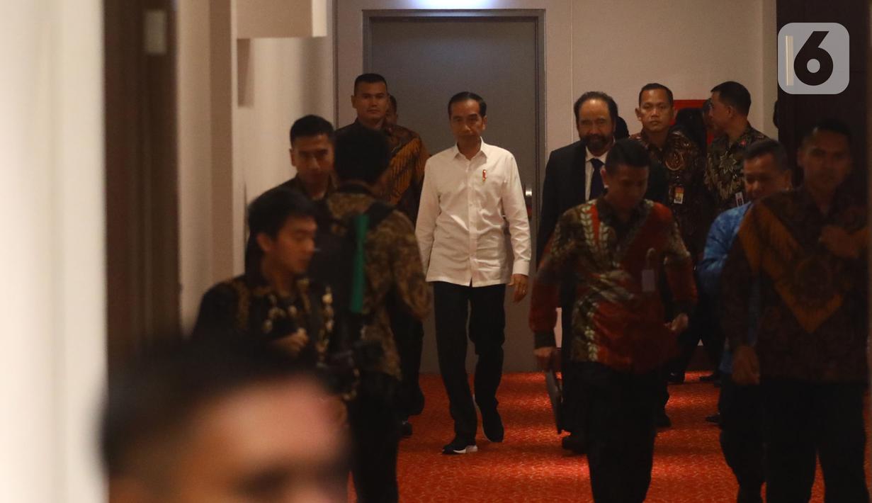 Presiden Joko Widodo atau Jokowi (kiri) didampingi Ketua Umum Partai Nasdem Surya Paloh (kanan) saat menghadiri perayaan ulang tahun ke-8 Partai Nasdem di JIExpo, Jakarta, Senin (11/11/2019). Surya Paloh menyambut langsung kedatangan Jokowi di HUT Nasdem. (Liputan6.com/Angga Yuniar)