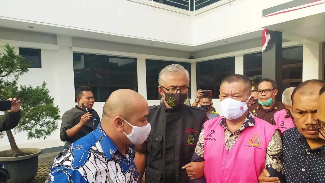 Dengan menggunakan baju tahanan berwarna orange dan tangan terborgol, Kepala Dinas Pemuda dan Olahraga Garut Kuswensi, memasuku kendaraan tahanan Kejaksaan Negeri Garut.