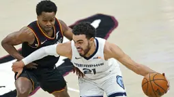 Pebasket Memphis Grizzlies, Tyus Jones, berebut bola dengan pebasket Cleveland Cavaliers, Yogi Ferrell, pada laga NBA, Senin (11/1/2021). Grizzlies menang dengan skor 101-91. (AP/Tony Dejak)