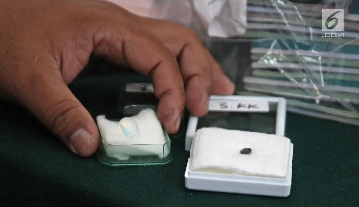 Petugas menunjukkan batu perhiasan milik bos First Travel saat sidang di PN Kota Depok, Jawa Barat, Senin (23/4). Dalam catatan Jaksa kasus penipuan First Travel ini telah menimbulkan kerugian sampai Rp 905,3 miliar. (Liputan6.com/Herman Zakharia)